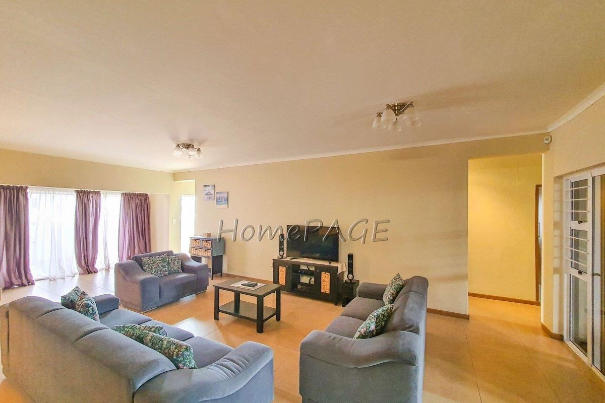 Spacious living room featuring tiled flooring, neutral wall tones, and large sliding glass doors providing access to the outdoor area.