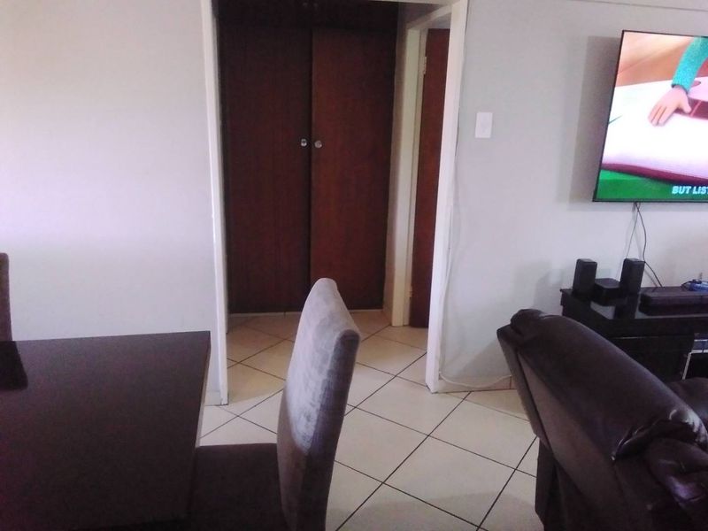 A living area featuring tiled flooring and a built-in cupboard, providing a functional space for relaxation and storage.