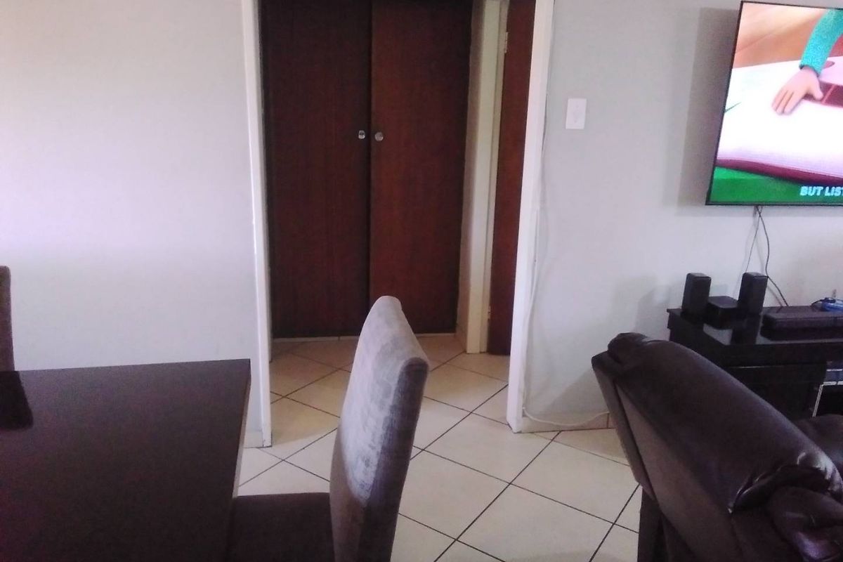 A living area featuring tiled flooring and a built-in cupboard, providing a functional space for relaxation and storage.