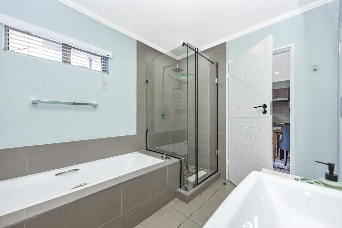 Modern bathroom featuring a built-in bathtub, a separate glass-enclosed shower with a rain shower head, and contemporary tiled finishes.