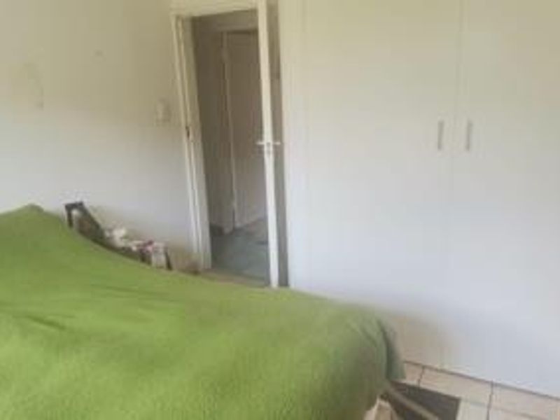 A bedroom featuring built-in cupboards and tiled flooring, requiring cosmetic updates to improve the overall aesthetic and condition of the space.