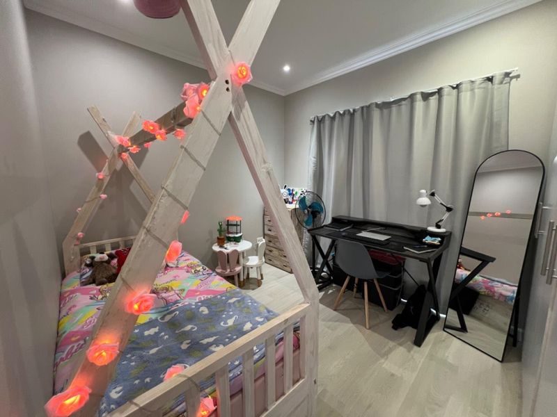 A well-maintained bedroom featuring light-toned laminate flooring, recessed downlighting, and decorative cove cornicing.