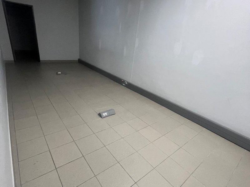 An empty, vacant office space featuring tiled flooring, a suspended ceiling, and floor-mounted electrical outlets, ready for custom fit-out.