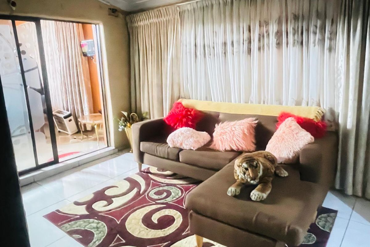 A living room featuring tiled flooring and large sliding glass doors that provide access to an adjacent patio area.