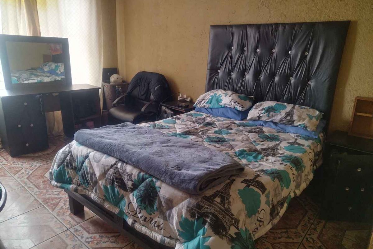 A bedroom featuring tiled flooring and textured wall finishes, providing a functional sleeping space.