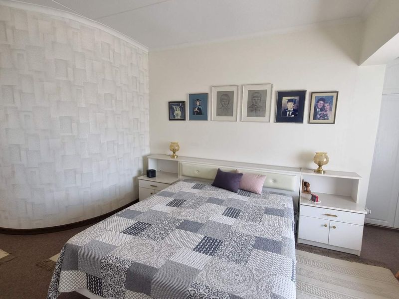 A well-maintained bedroom featuring built-in cupboards, textured accent wallpaper, and coving detail, offering a functional and comfortable living space.