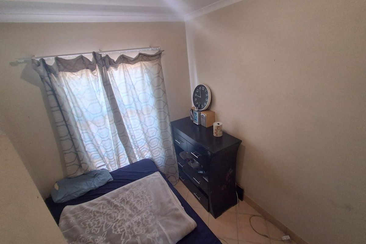 A compact bedroom featuring tiled flooring and neutral wall finishes, providing a functional space with natural light from the window.