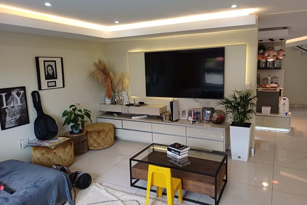 Modern living room featuring tiled flooring, recessed ceiling lighting with cove accents, and a sleek built-in media console.