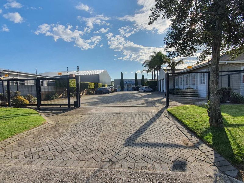 A well-maintained commercial office property entrance featuring a paved driveway, secure perimeter fencing, and professional signage.