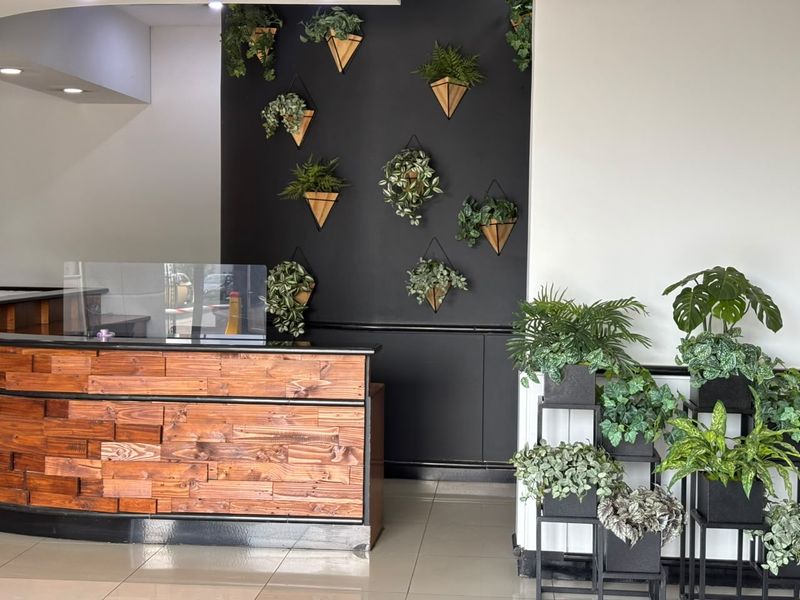 A professional office reception area featuring a custom wood-paneled desk, tiled flooring, and a modern black accent wall with decorative wall-mounted planters.