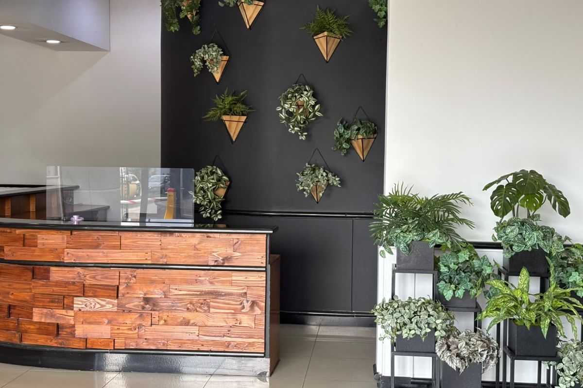 A professional office reception area featuring a custom wood-paneled desk, tiled flooring, and a modern black accent wall with decorative wall-mounted planters.