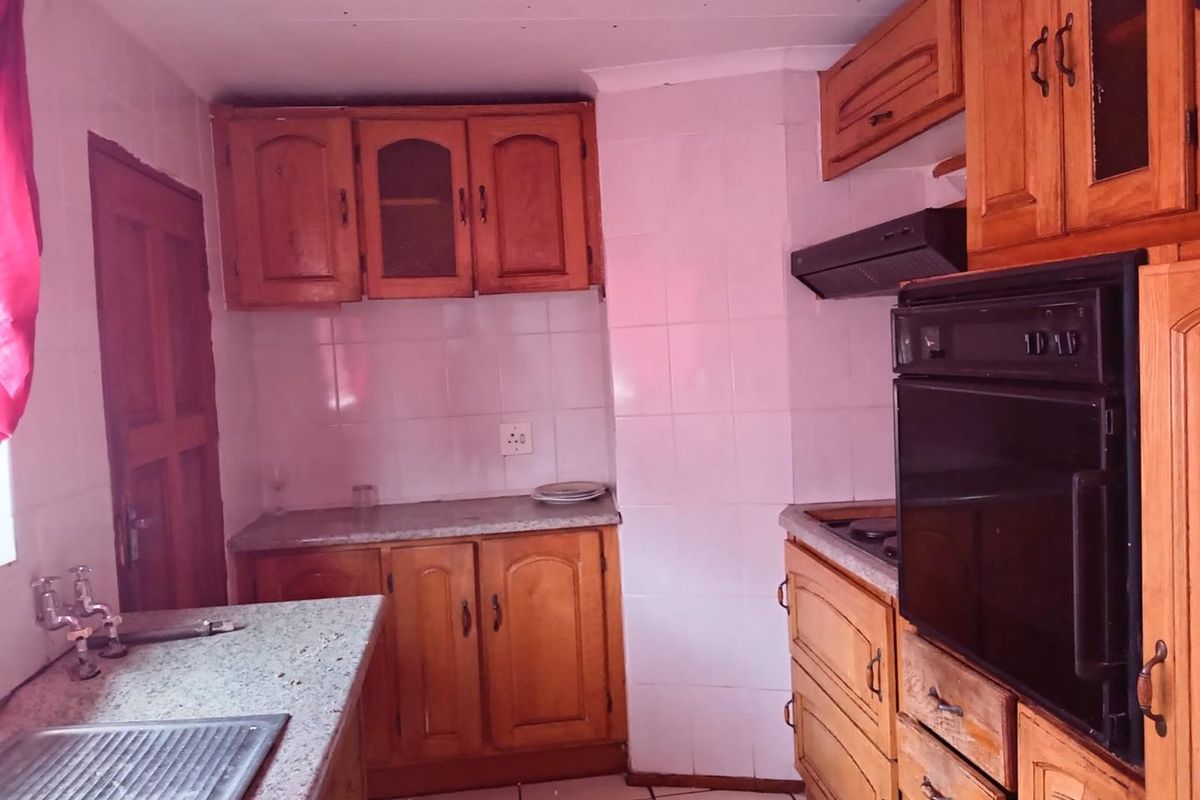 A dated kitchen featuring wooden cabinetry, granite-look countertops, a built-in oven, and a tiled backsplash.