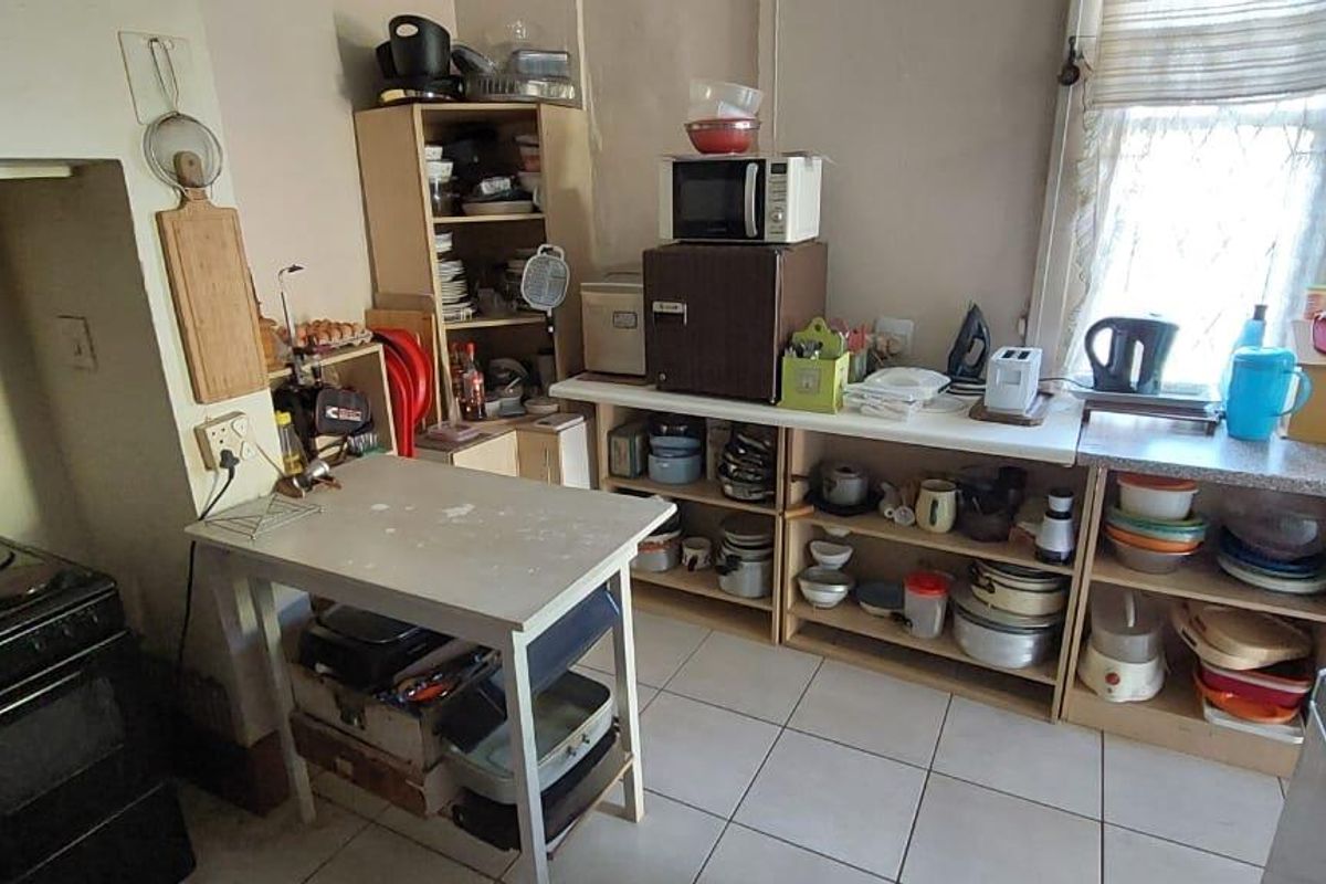 A functional kitchen area featuring tiled flooring, a freestanding stove, and open-style cabinetry providing basic storage and preparation space.