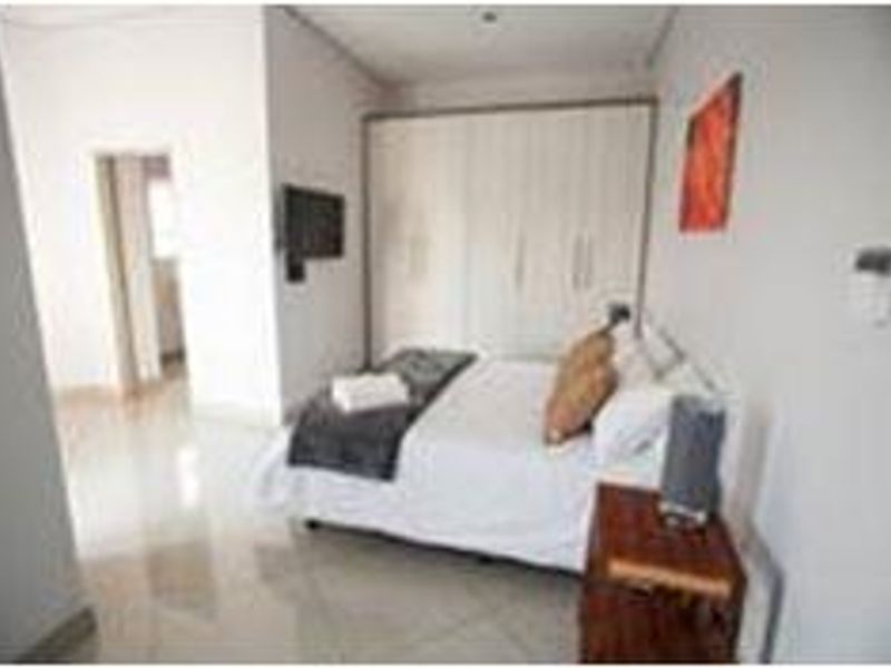 A well-lit bedroom featuring neutral tiled flooring and ample built-in cupboard storage space.