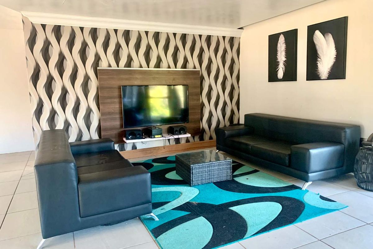A living room featuring a built-in media wall unit, tiled flooring, and decorative wallpaper.