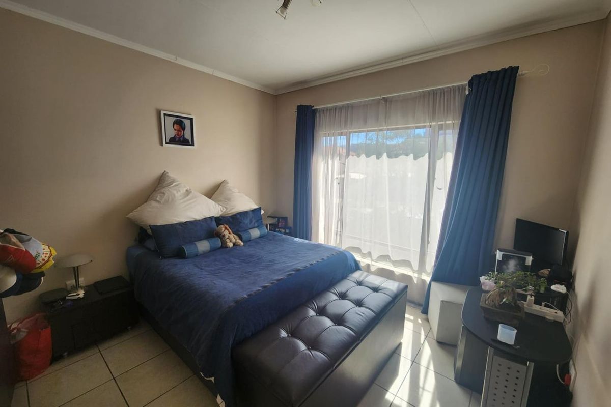 A bedroom featuring tiled flooring and a large window with curtain tracks, providing natural light.