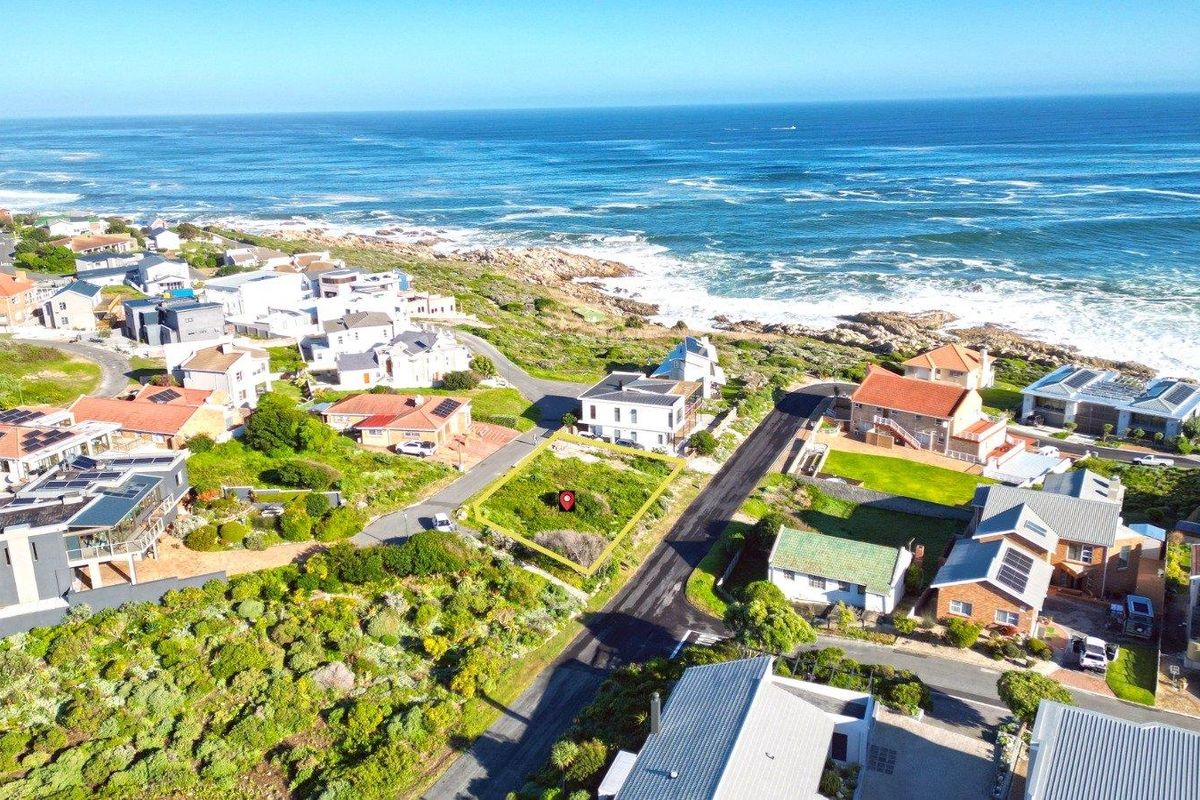 An aerial view of a vacant residential plot situated in a coastal neighborhood, highlighting its proximity to the ocean and surrounding residential development.