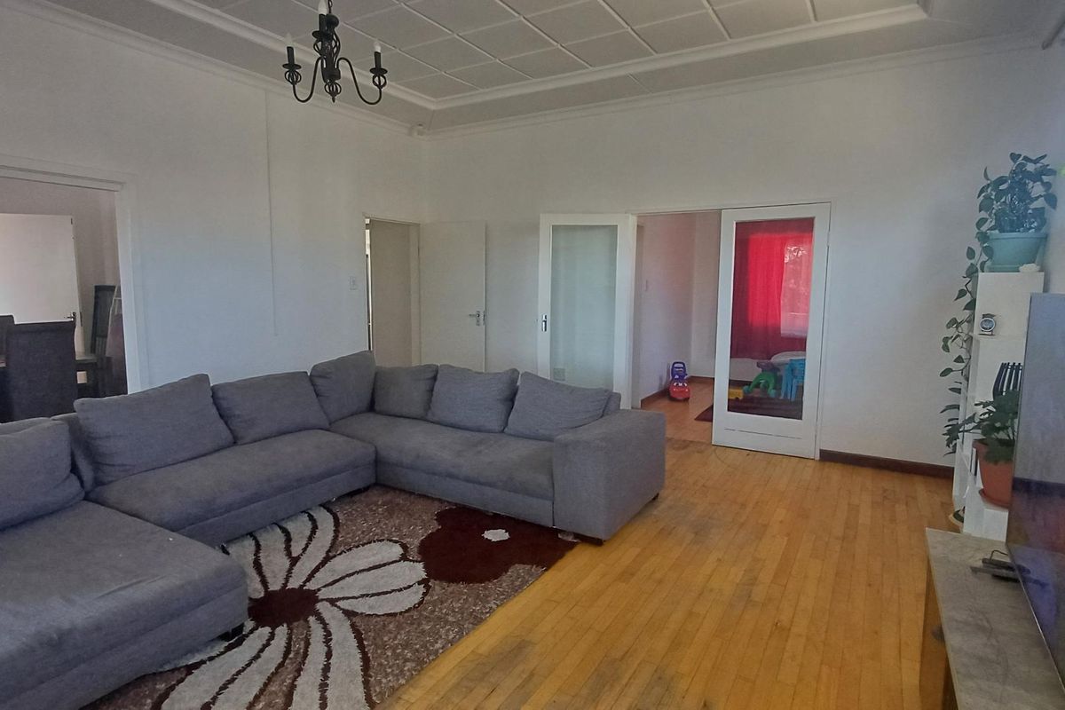 Spacious living room featuring original hardwood flooring, a decorative coffered ceiling, and classic french doors leading to adjacent rooms.