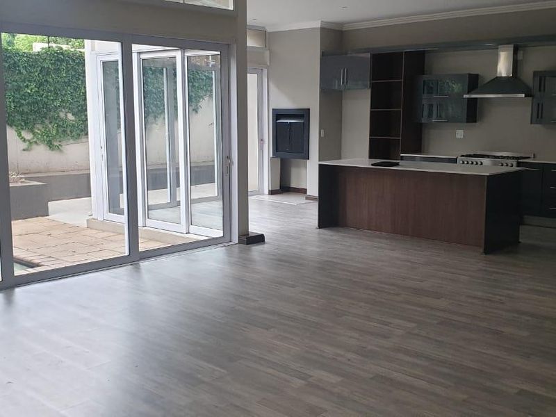 Spacious open-plan living area featuring a modern kitchen with island, built-in fireplace, and large sliding doors opening to a patio and pool area.