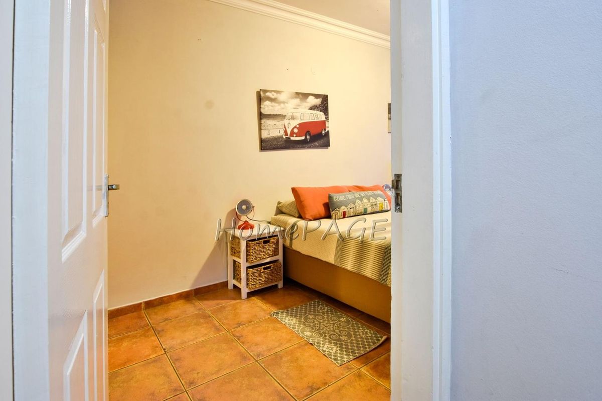 A view into a bedroom featuring terracotta floor tiles and a neutral wall finish, accessed through a standard interior door.