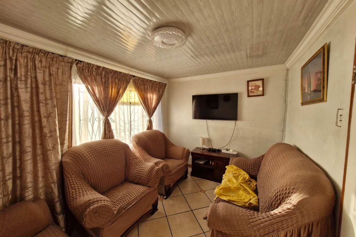 A compact living room featuring tiled flooring, a textured ceiling, and wall-mounted television setup.