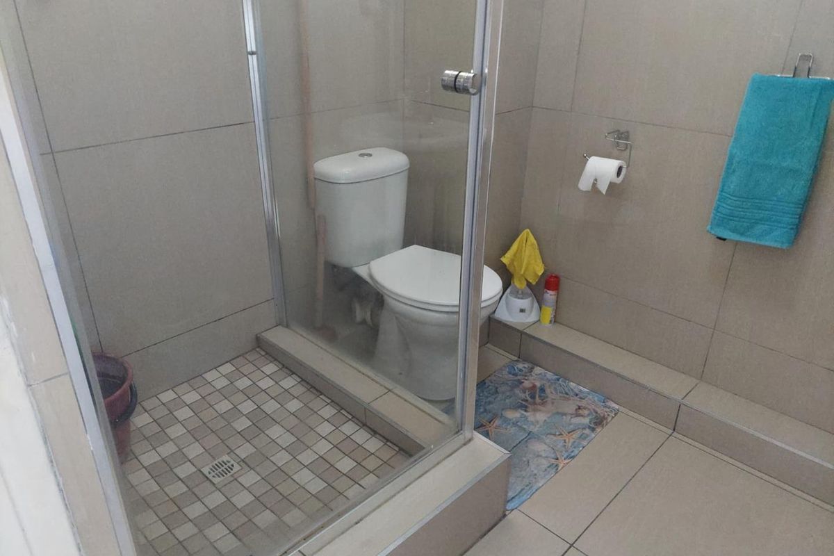 A functional bathroom featuring a glass-enclosed shower, tiled walls, and floor tiling, providing a clean and practical space.