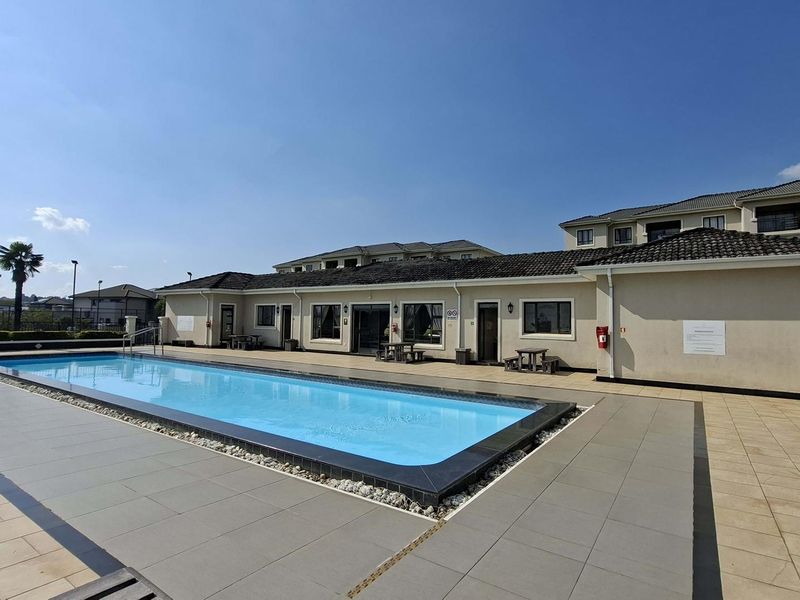 A well-maintained communal swimming pool area featuring tiled decking and direct access to the apartment complex facilities.