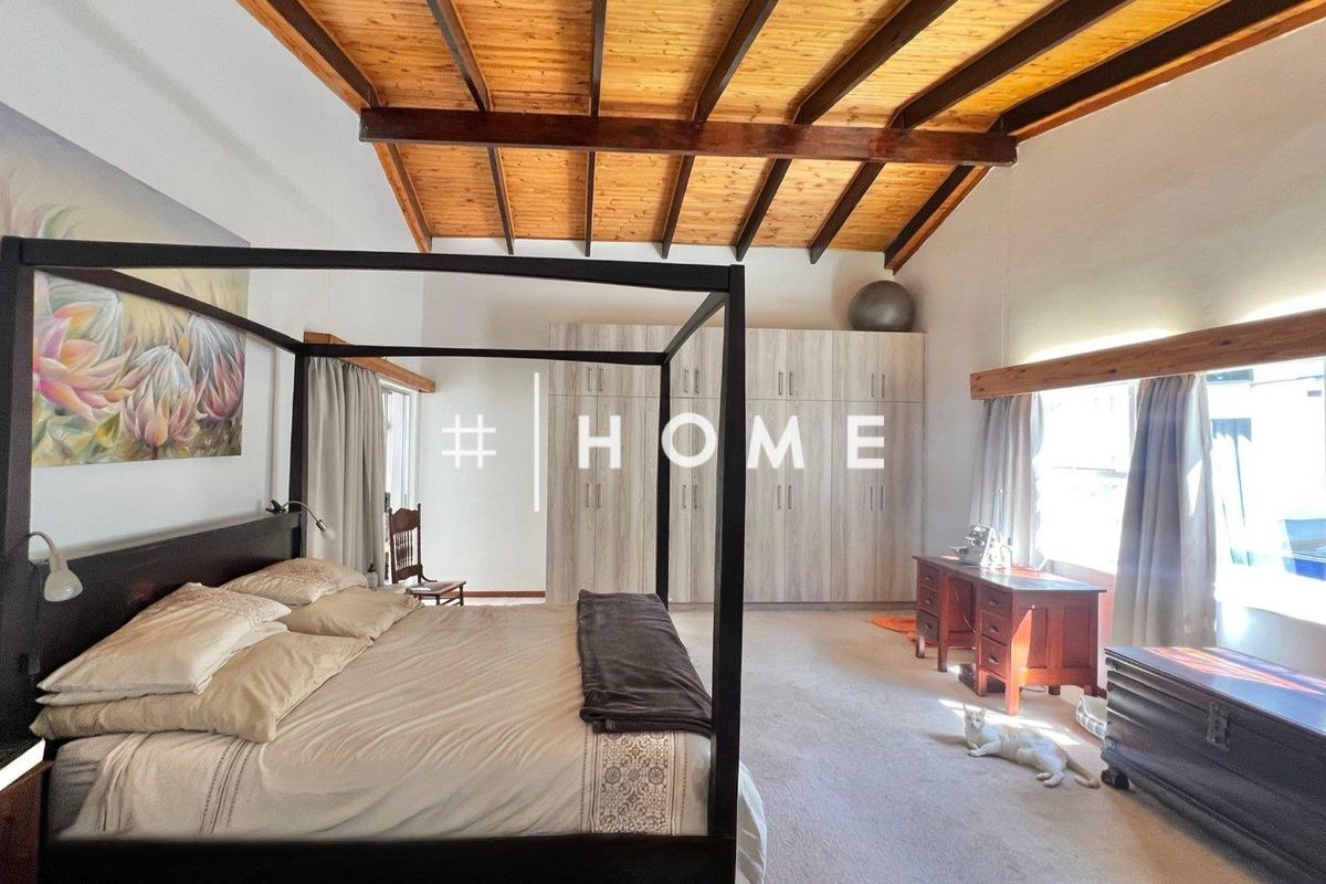 Spacious bedroom featuring high vaulted timber-beamed ceilings and extensive built-in cabinetry, offering a warm and airy atmosphere.