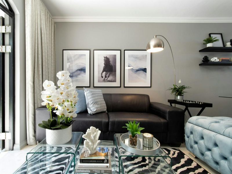 A well-maintained living room featuring crown molding, floating wall shelves, and a large sliding glass door providing access to the exterior.