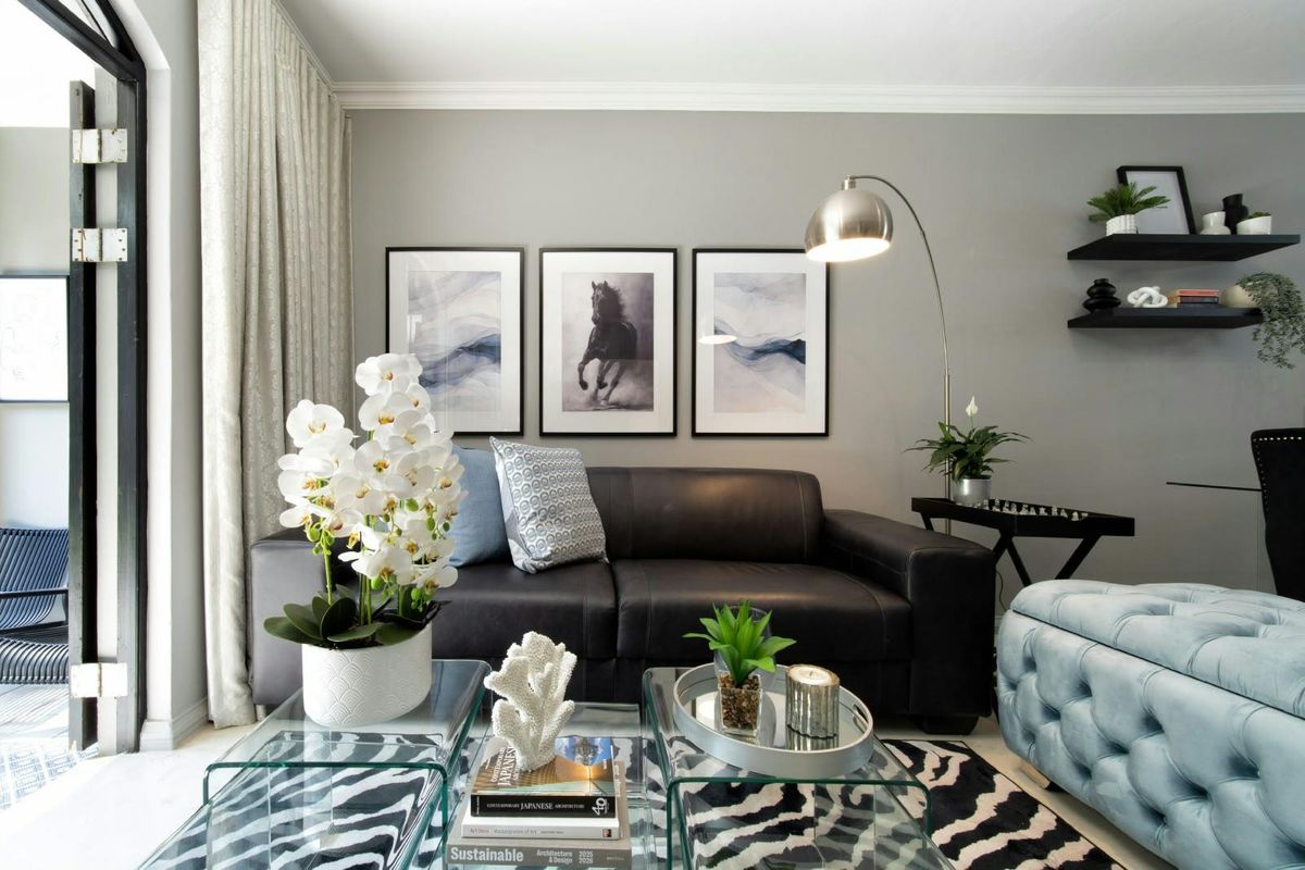 A well-maintained living room featuring crown molding, floating wall shelves, and a large sliding glass door providing access to the exterior.
