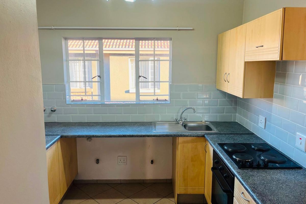 Functional kitchen featuring light wood cabinetry, dark laminate countertops, subway tile backsplash, and integrated electric hob and oven.