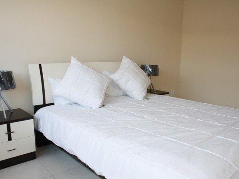 A simple bedroom featuring neutral wall tones and tiled flooring, providing a clean and functional space.