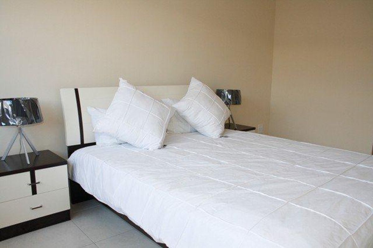 A simple bedroom featuring neutral wall tones and tiled flooring, providing a clean and functional space.