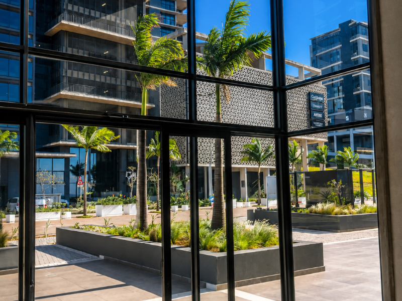 Modern entrance lobby featuring floor-to-ceiling glass walls with views of the landscaped courtyard and surrounding commercial architecture.