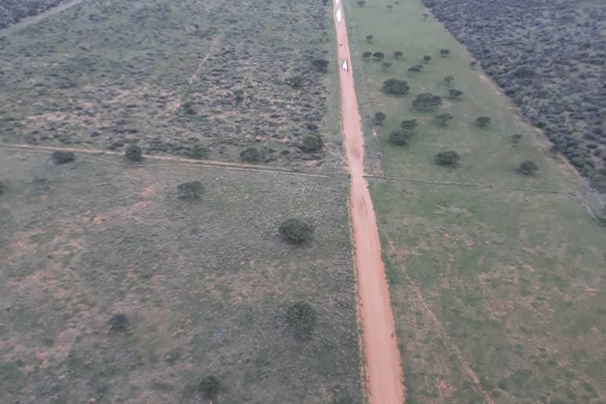 Aerial view of the expansive farm property, showcasing the long dirt access road and surrounding natural landscape.