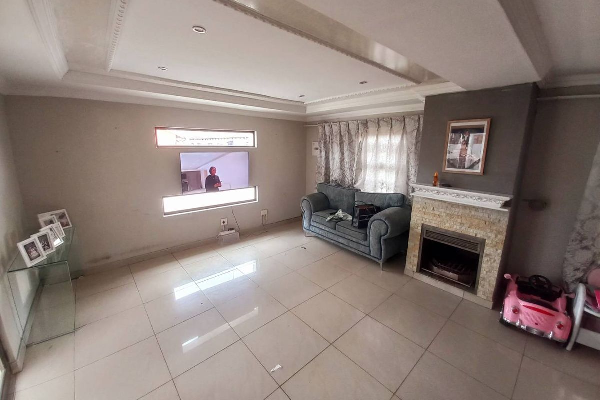Spacious living room featuring tiled flooring, a built-in fireplace with stone cladding, recessed ceiling detail, and integrated wall-mounted television niche.
