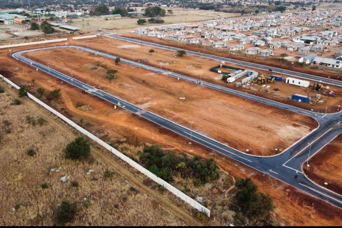 An aerial view of a developing residential estate featuring newly paved roads and cleared plots ready for construction.
