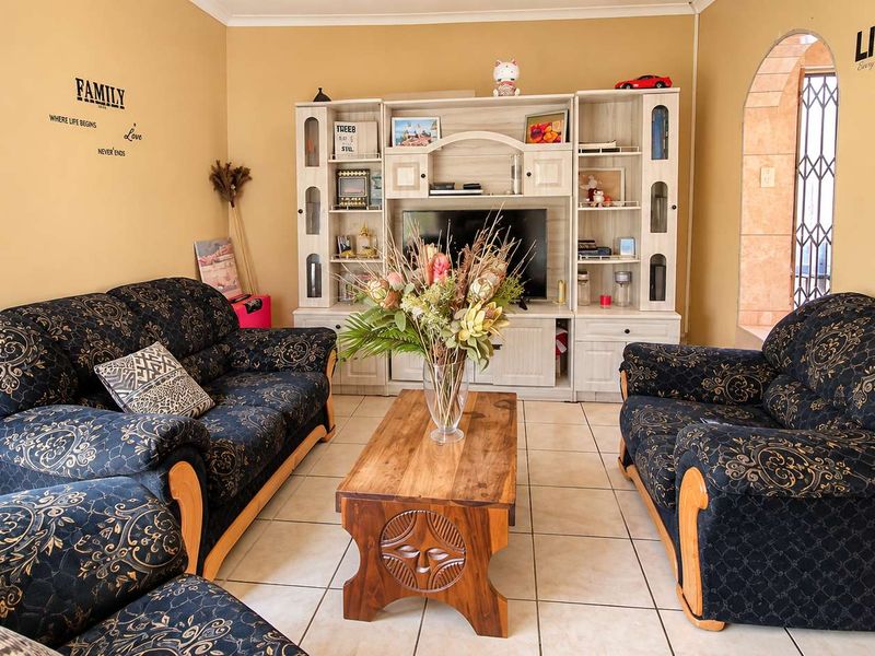 A comfortable living room featuring ceramic floor tiles and an arched doorway leading to an adjacent space.