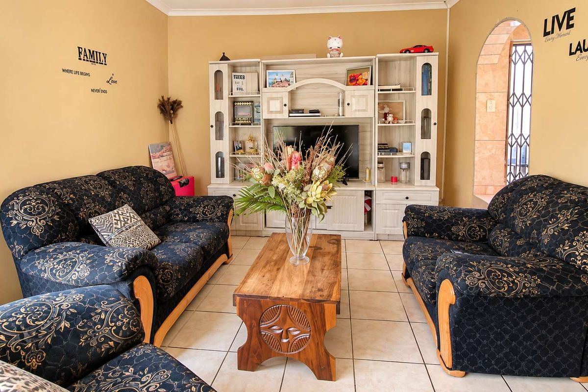 A comfortable living room featuring ceramic floor tiles and an arched doorway leading to an adjacent space.