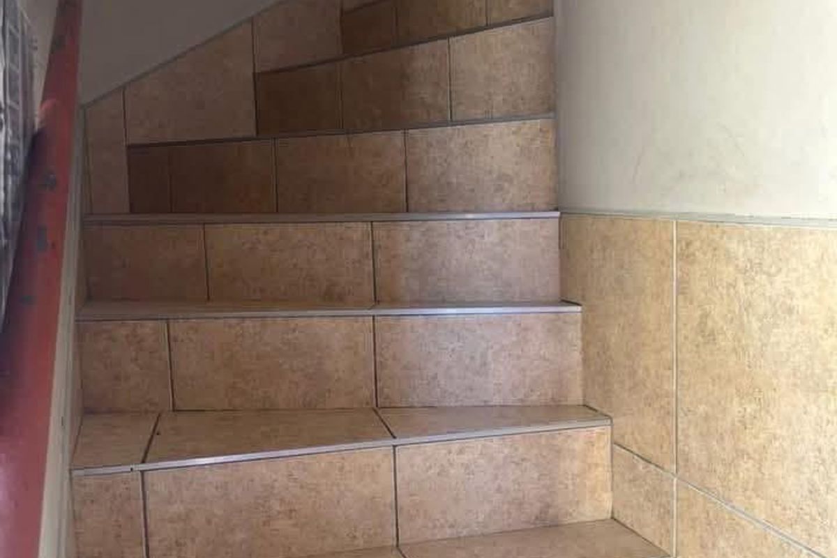 A functional staircase featuring tiled steps and a metal handrail, providing access within the apartment building.