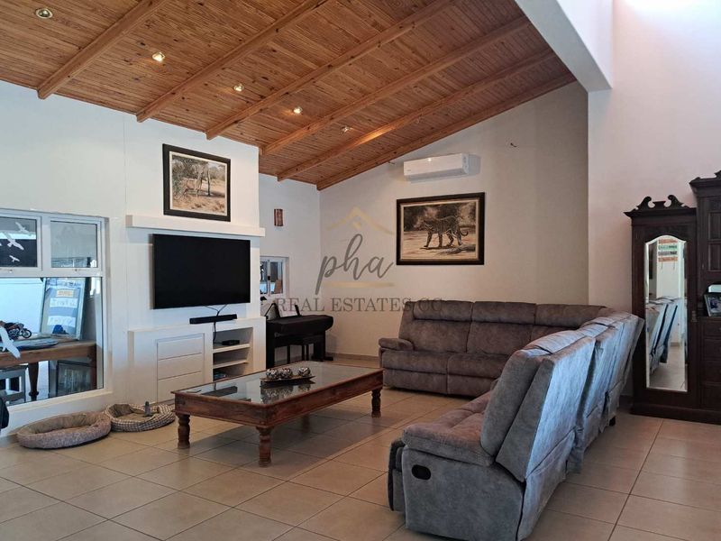 Spacious living room featuring a high exposed timber beam ceiling, tiled flooring, built-in media cabinetry, and a wall-mounted air conditioning unit.