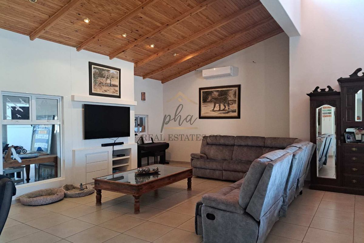Spacious living room featuring a high exposed timber beam ceiling, tiled flooring, built-in media cabinetry, and a wall-mounted air conditioning unit.