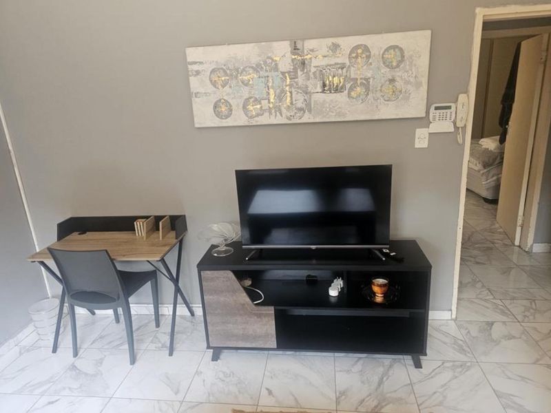 A living area featuring light-colored marble-effect floor tiles and a wall-mounted security alarm system.
