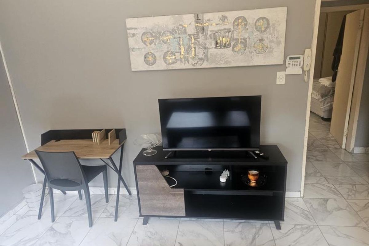 A living area featuring light-colored marble-effect floor tiles and a wall-mounted security alarm system.