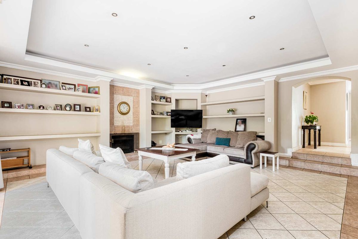 Spacious living room featuring built-in shelving, a tiled fireplace, recessed ceiling lighting, and tiled flooring with a step-up transition to the hallway.