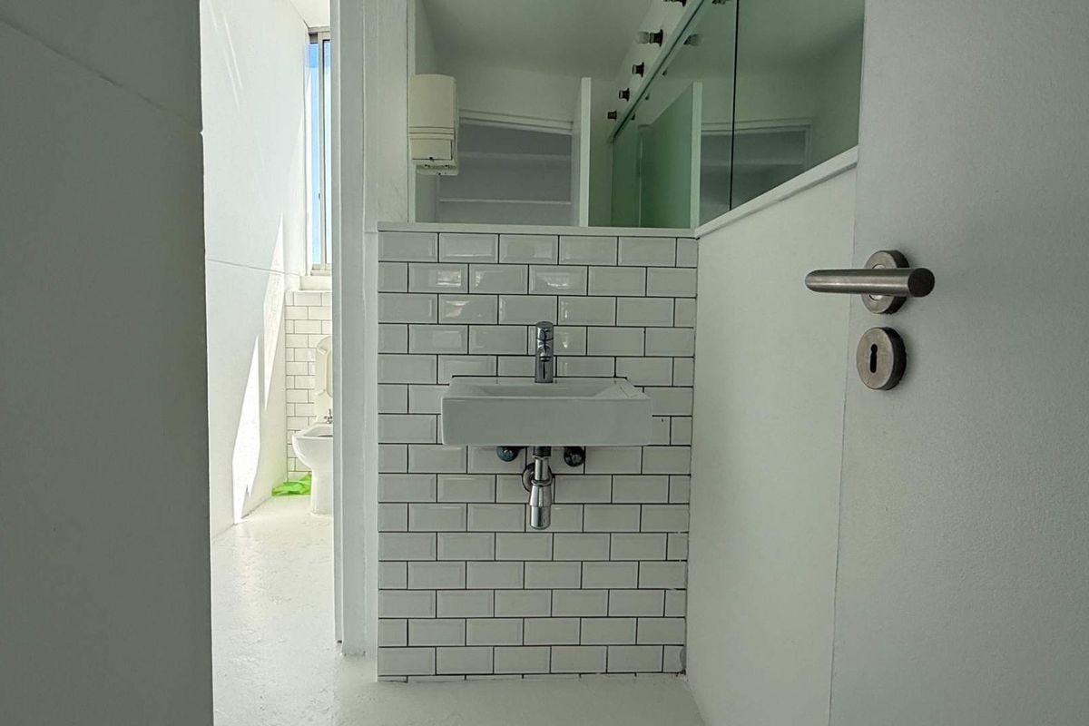 A clean, modern bathroom featuring a wall-mounted basin with a white subway tile backsplash and a minimalist design.