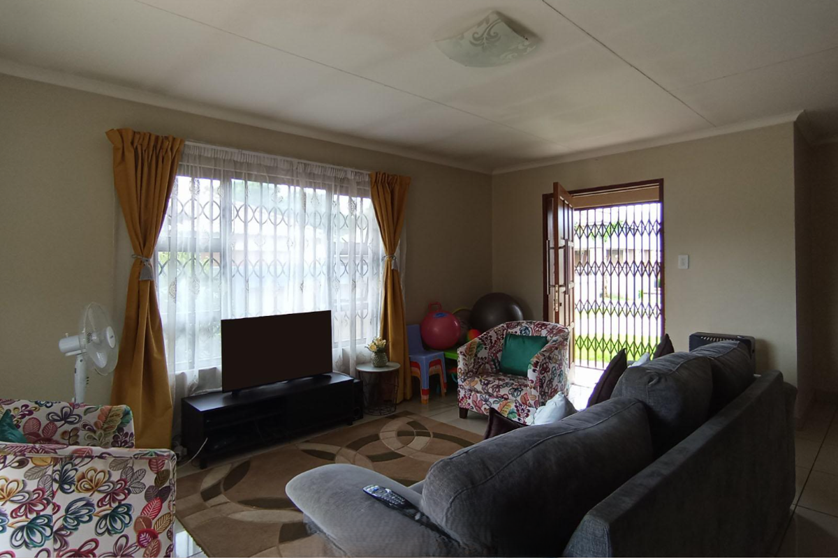 A living room featuring tiled flooring, a large window with security bars, and a security gate at the entrance.