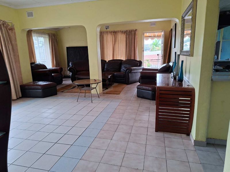 Spacious open-plan living area featuring tiled flooring and arched architectural details, providing a versatile layout with direct access to an outdoor space.