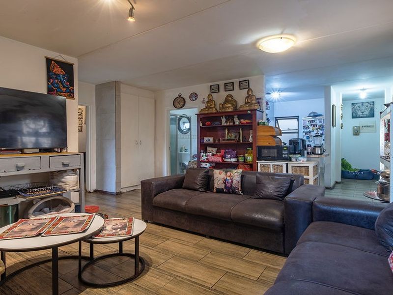 Open-plan living area featuring tiled flooring and neutral wall finishes, providing a functional space that connects to the kitchen and hallway.