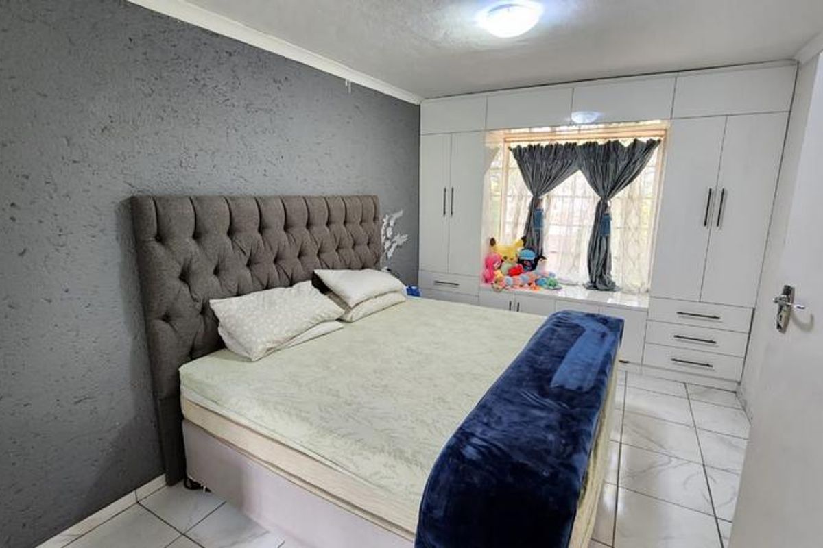 A well-maintained bedroom featuring built-in white cabinetry, a window seat, and tiled flooring, providing ample storage and a functional layout.